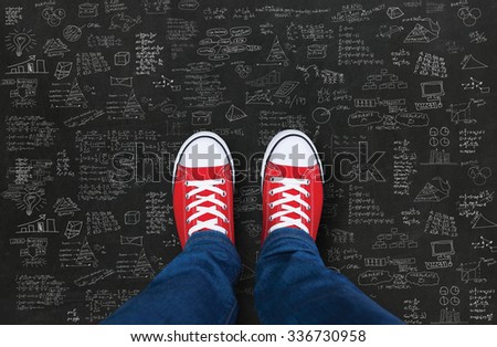 Feet wearing red shoes on black background with business plan