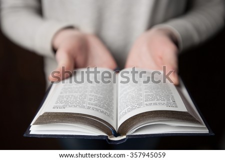 woman hands on bible. she is reading and praying over bible in a dark space over wooden table
