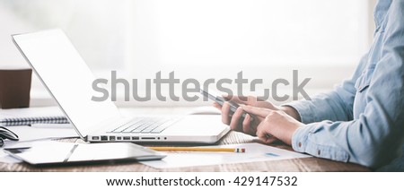 Website developer working using  laptop at the office on wooden table. Film effect
