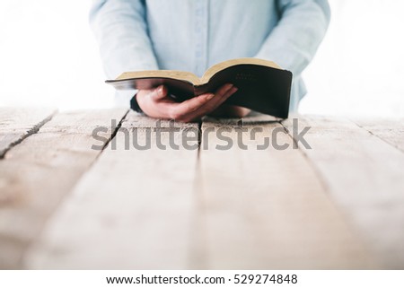 Bible in hands of a woman. She is reading and praying over it