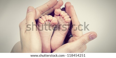 Small feet baby holds his mother in her hands