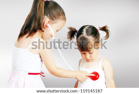 Two pretty little girls playing doctor