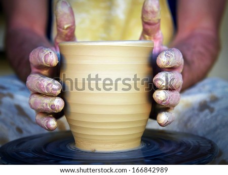 Close-up of potter\'s hands with the product on a potter\'s wheel