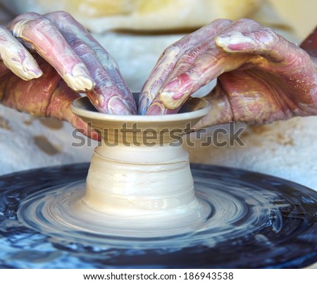 Close-up of potter\'s hands with the product on a potter\'s wheel