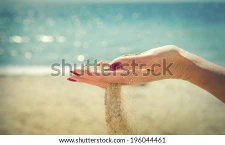 Beautiful female hand and the sand on the sea background