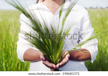 Young cute woman holding ears of wheat in the hands