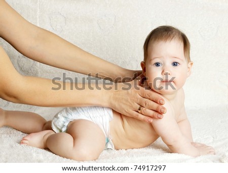 Mother massaging body of newborn baby - indoors