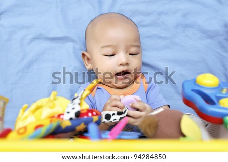 Cheerful cute baby boy playing with hanging toys.