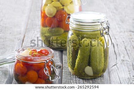 Composition with jars of pickled vegetables on wooden tables. Marinated food