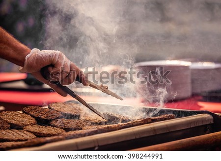 Chef  preparing burgers at the barbecue outdoors