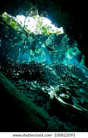 Silhouette of a lone female snorkeler from inside an underwater cave system in mexico.