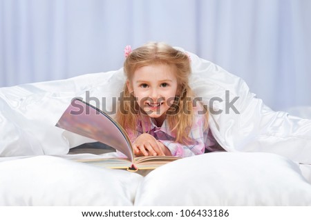 Little girl read the book in the bed