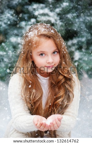Beautiful girl catches snowflakes