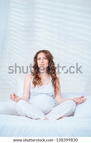 Pregnant woman sit on bed