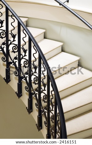 metal railing of curved staircase inside of large mansion