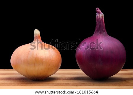 Purple and white onion on wooden board, with black background