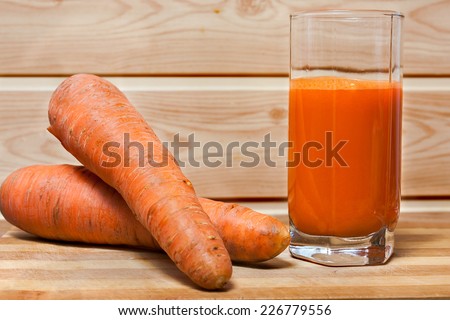 Fresh squeezed carrot juice on wooden background, with natural carrots and juice in a glass