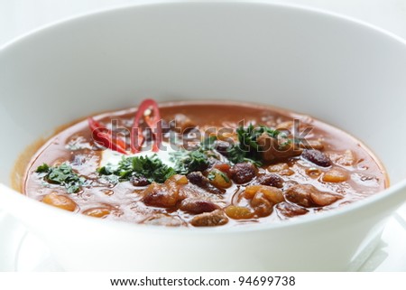 Hot soup in the white dish on wooden table