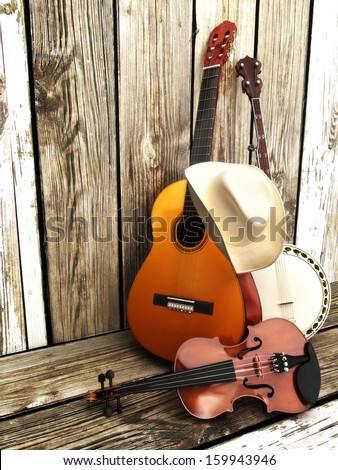 Country Music Background With Stringed Instruments. Guitar, Banjo , Violin And A Cowboy Hat Leaning Against A Wood Fence. Room For Text Or Copy Space.