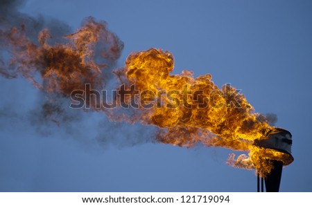 Flame torch and blue sky - environment pollution. Ecology damage.