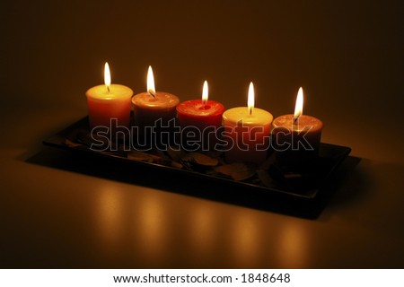 Five candles in a candle holder photographed in the dark while lit.