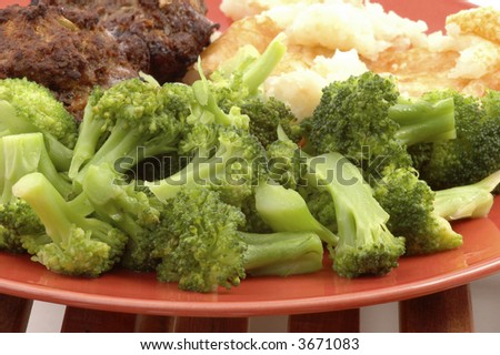 Fresh steamed broccoli on an orange plate.