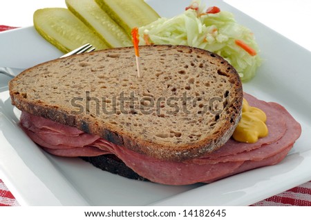 Deli sandwich served with pickles and coleslaw.