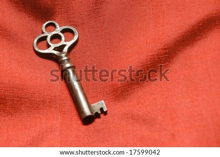 isolated vintage key on red satin background