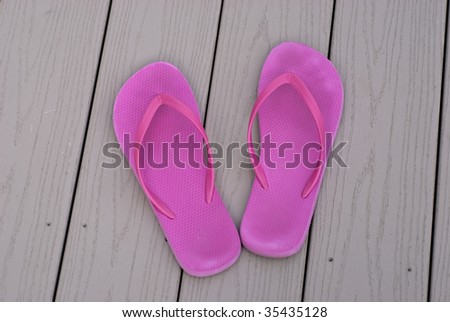 two pink summer flip flops on pool deck