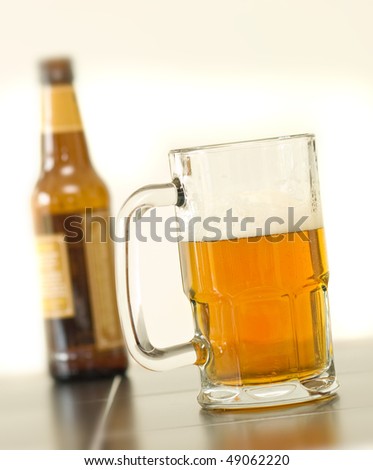 frosty mug of beer drink on table with bottle