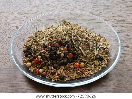 Mix of spices in glass saucer isolated on dark wooden table