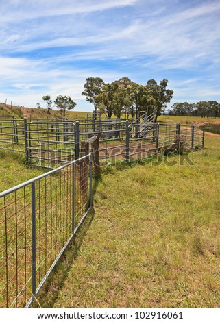 Australian farming scene with cattle fences and pens against a cloudy blue sky.