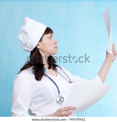 Nice nurse looks at document on blue background