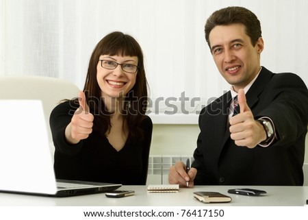 Two business people doing the ok sign in office