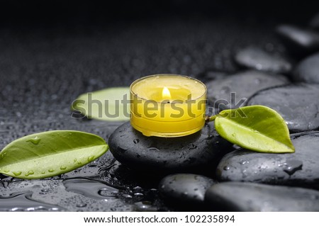 spa concept with candle and zen stones and green leaf on zen stones
