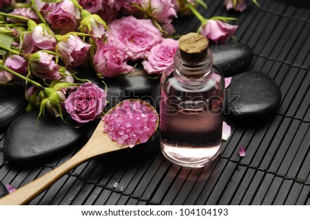 Branch rose with salt in bowl and massage oil on mat