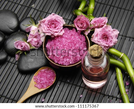 Pink rose with salt in bowl and massage oil ,grove on green mat