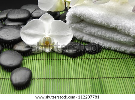 White orchid and stones with white towel on green mat
