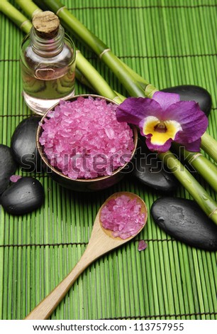 Pink orchid with salt in bowl and massage oil ,grove on green mat