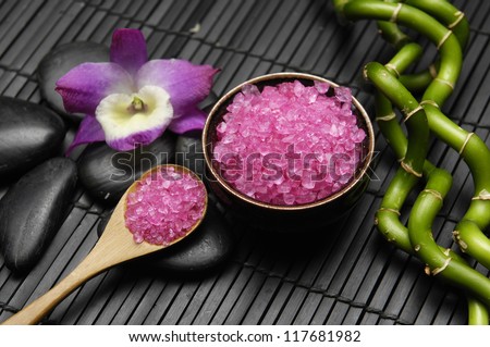 Lying down lucky bamboo and orchid with zen stone and pink salt in spoon on mat