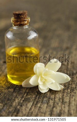White Gardenia Blossom with spa oil in glass on driftwood