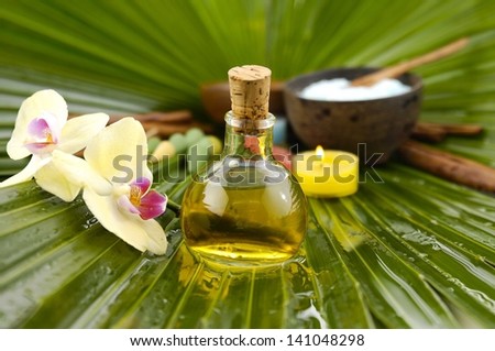 Spa set with, spa oil , salt in bowl, candle ,orchid on wet palm leaf