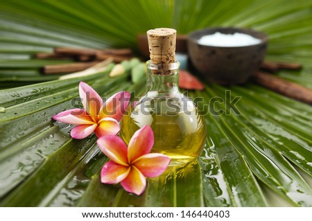 spa supplies with frangipani. cinnamon, salt in bowl, massage oil, wet palm