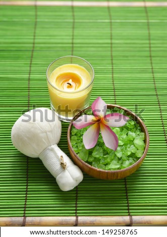 Pink frangipani with salt in bowl with massage ball and candle on mat