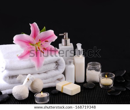 Pink lily and towel. Zen, candle, stones on black background