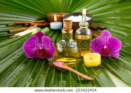 Spa set with, spa oil , salt in bowl , orchid ,candle, on wet palm leaf