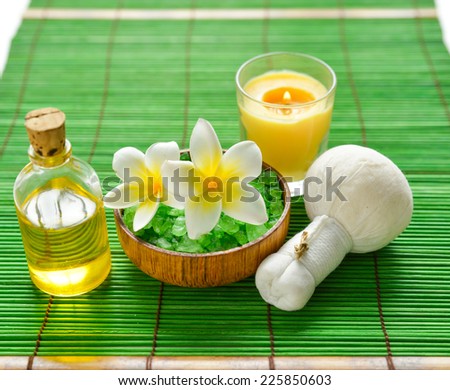 frangipani with salt in bowl with massage ball and candle on mat