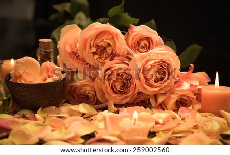 rose petals with candle with branch rose on towel on black background