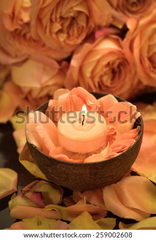 candle in bowl on rose petals and branch rose