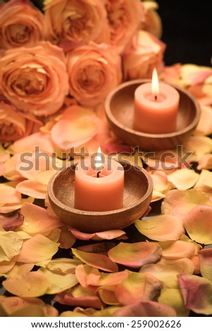 rose petals with rose with two candle in wooden bowl